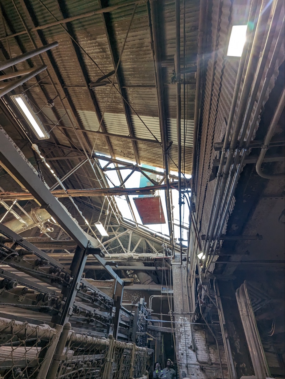 Interior view looking up through the removed roof section as the gearbox is lowered into position, crew in hard hats below