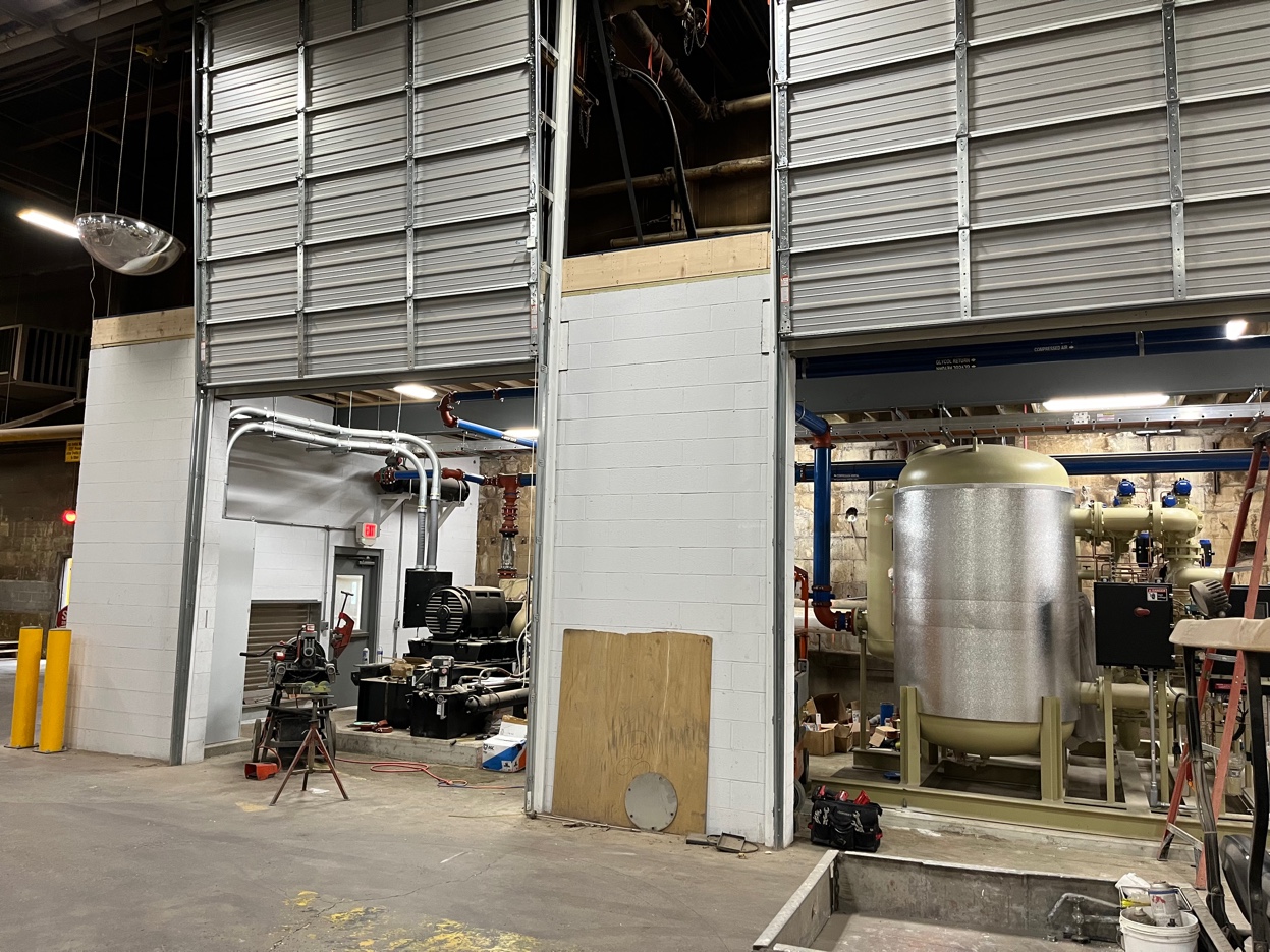 Wide view of the completed compressor room showing the new compressor, filtration vessels, and organized piping